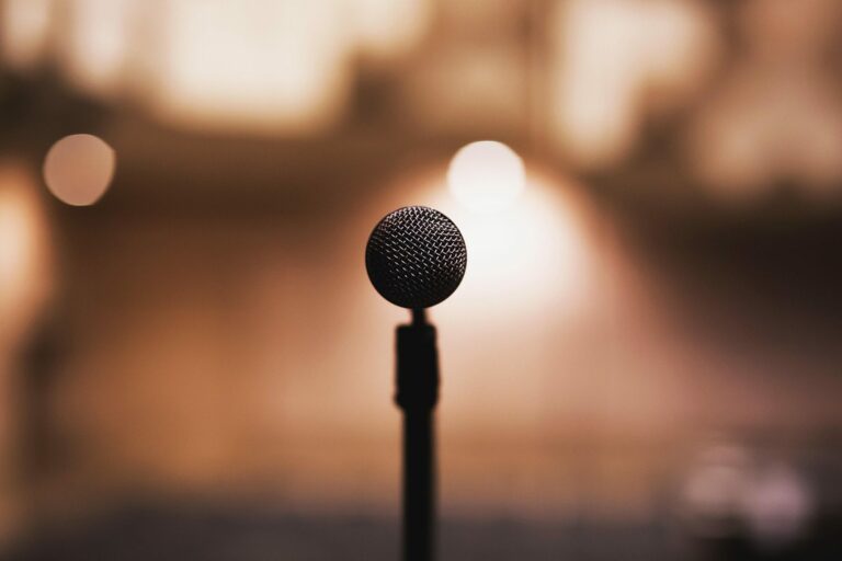 Microphone sur pied au centre d’une scène, devant des lumières chaudes et floues
