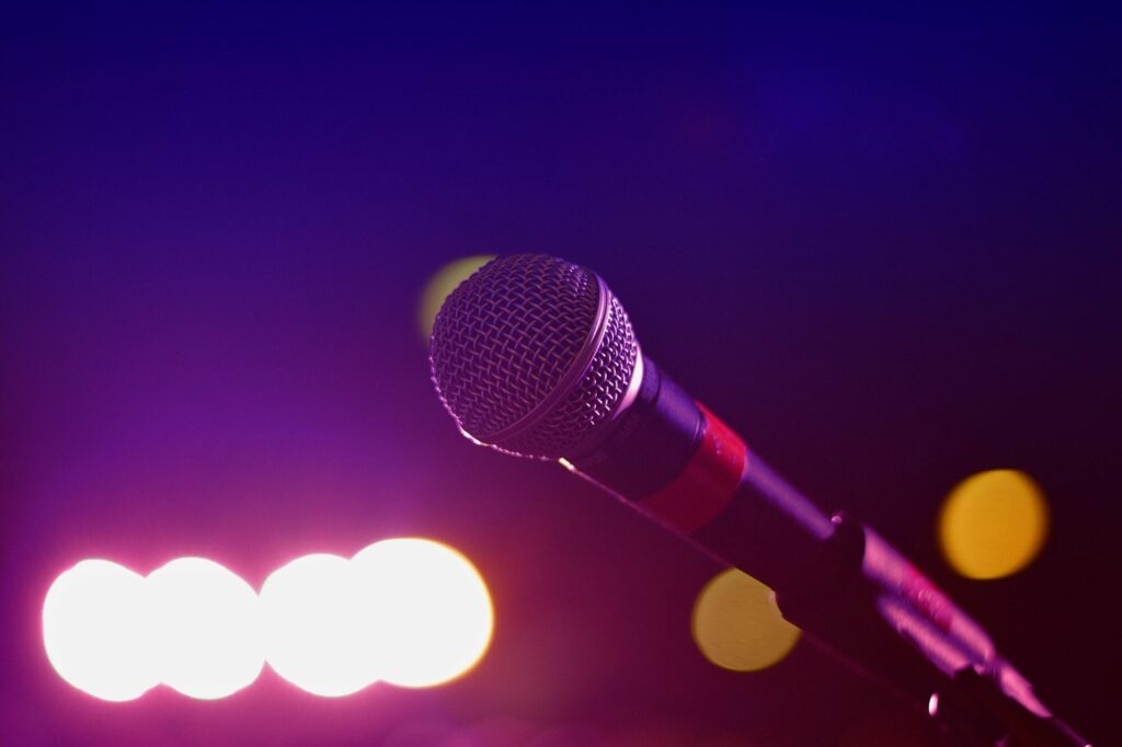 Microphone sur pied devant des projecteurs de scène flous aux reflets violets et orangés