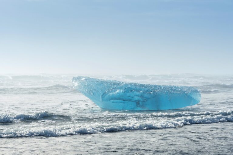Iceberg bleu pris dans une étendue d’eau glacée sous un ciel clair