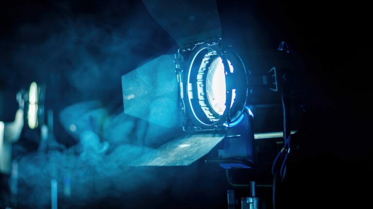 Projecteur de cinéma allumé sur un plateau de tournage, dans une lumière bleue traversée de fumée